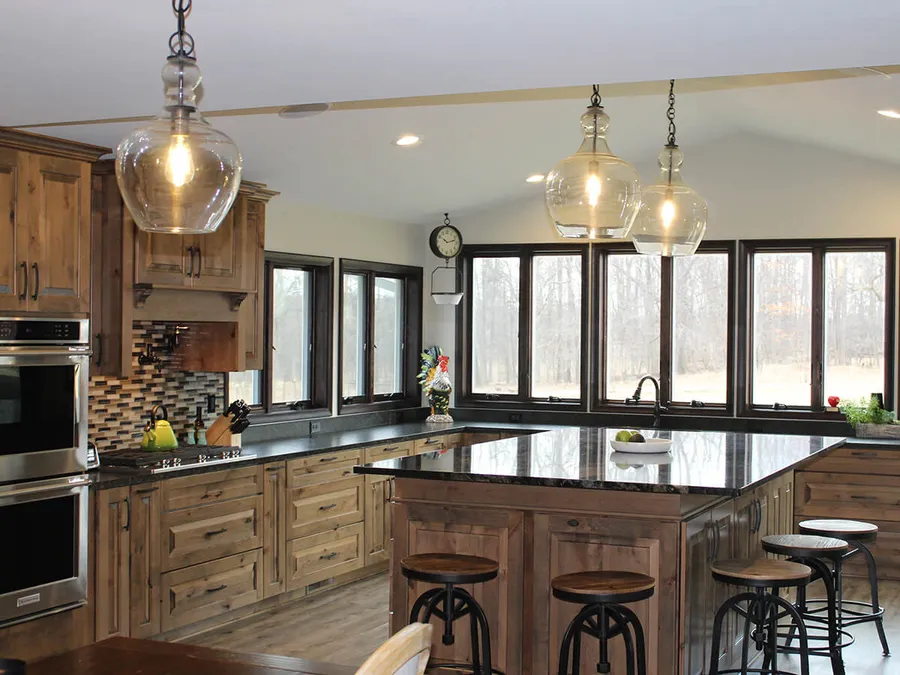 Rustic wood kitchen with dark granite island, glass pendants and industrial stools
