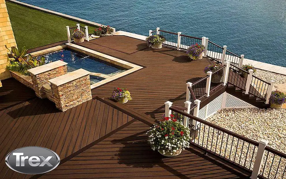 Multi-level waterfront deck with dark decking, white rail posts and a stone-edged spa