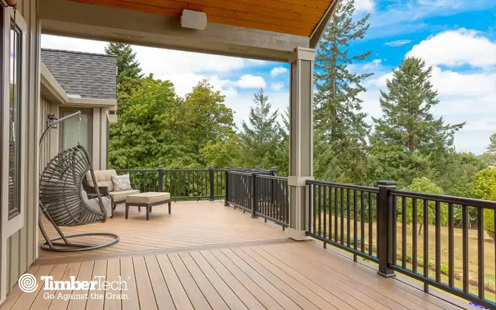Covered composite deck with black metal railing overlooking evergreen trees