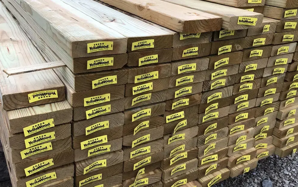 Stacked treated lumber boards with yellow YellaWood end tags