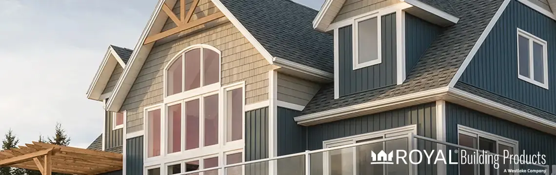 Home with blue vertical and tan shake siding, white trim and tall arched windows