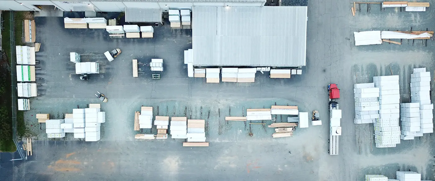 Overhead aerial view of a lumber yard with stacked materials and a warehouse