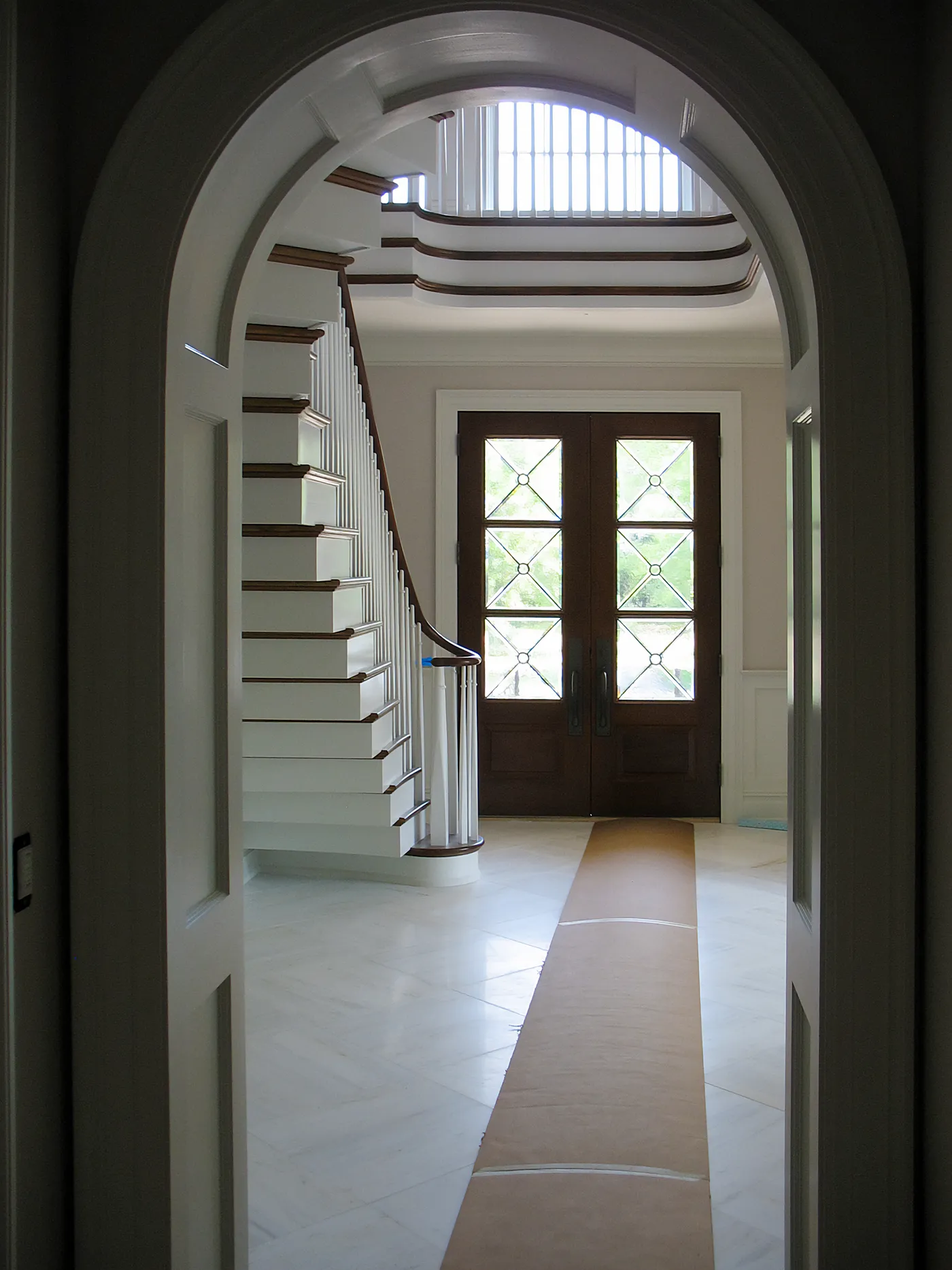 Arched doorway framing a curved staircase and double front doors in a foyer