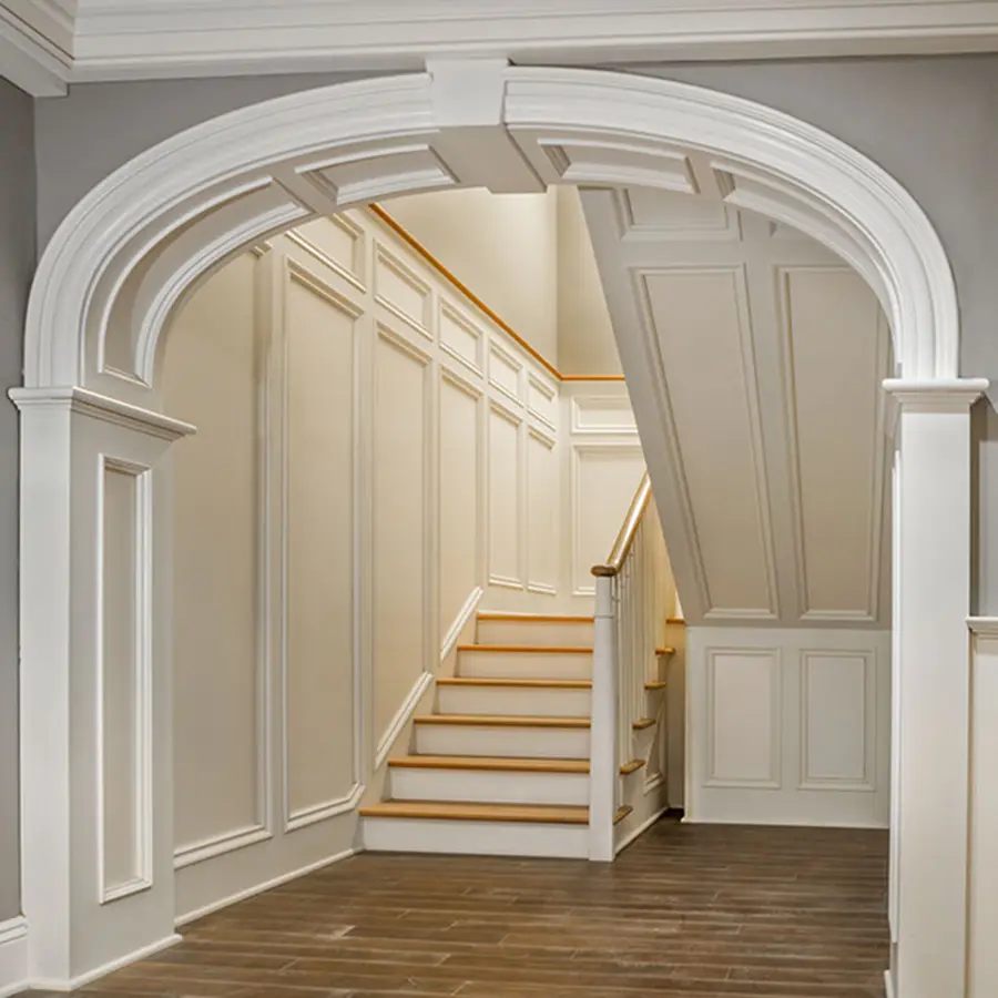 White molded archway opening to a staircase lined with raised wall panels