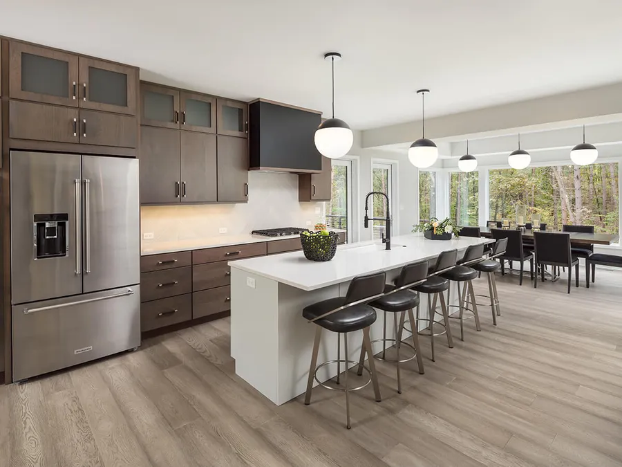 Open kitchen with dark wood cabinets, white island with bar stools and dining area