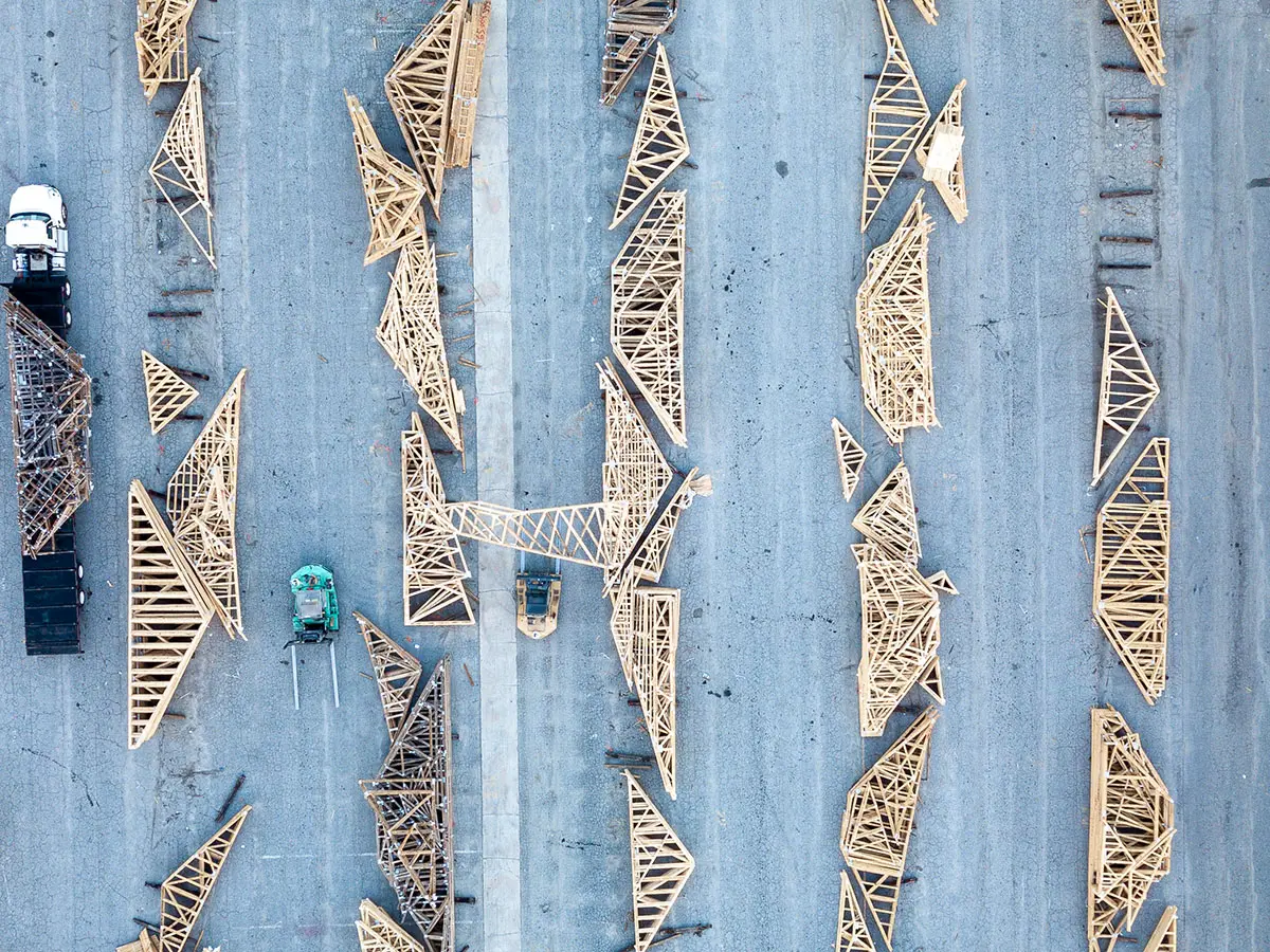 Aerial view of finished wood trusses laid out in rows on a yard
