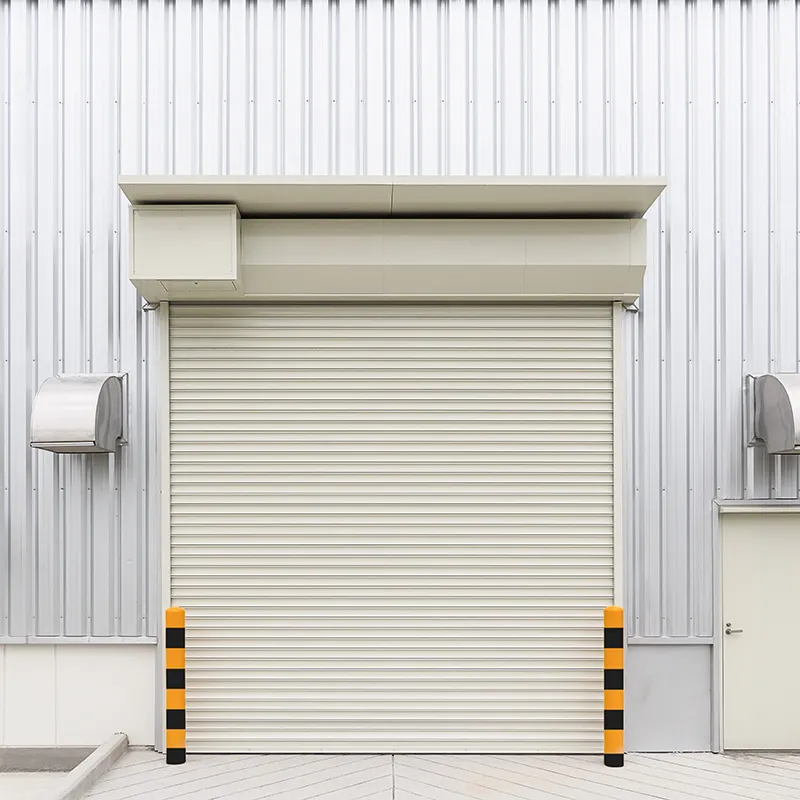 Roll-up commercial door on a corrugated metal building between safety bollards