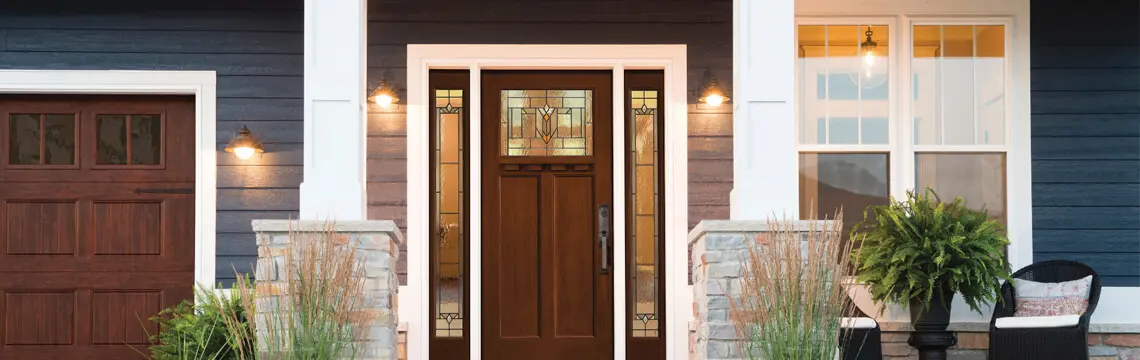Wood front door with leaded glass and sidelites on a navy-sided home