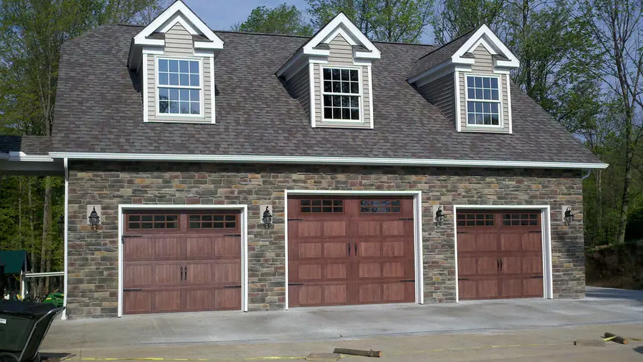 Three-car garage with stone front, wood-look carriage doors, and three dormers