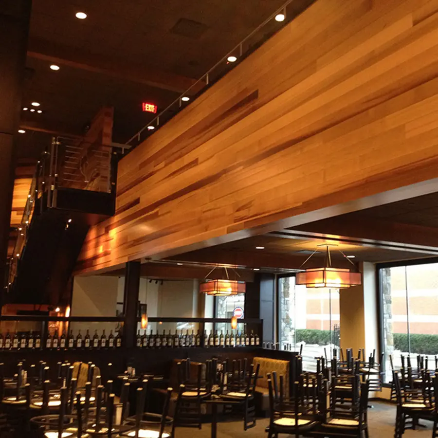 Restaurant dining room with a long wood-clad soffit and amber pendant lights