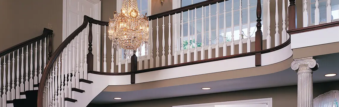 Two-story foyer with a curved staircase, white balusters and crystal chandelier