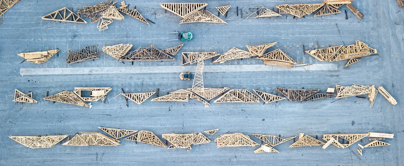 Overhead view of rows of roof trusses in a yard with a forklift