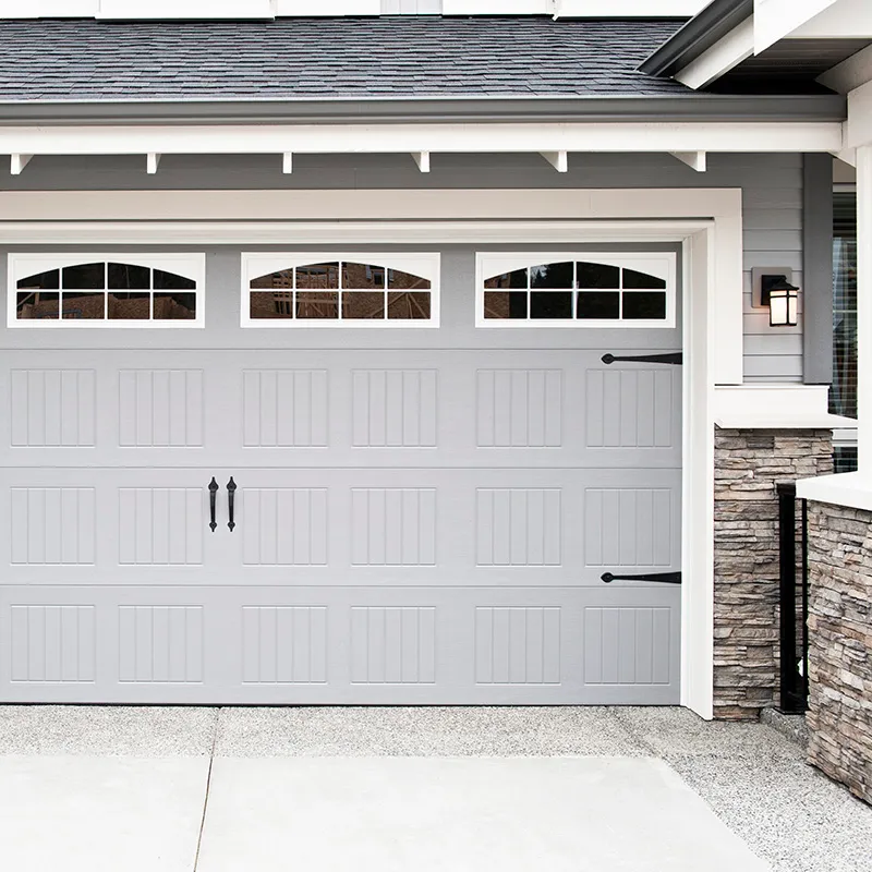 Gray carriage-style garage door with arched window lites and black hardware