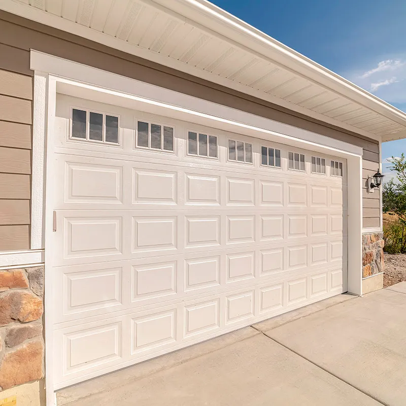 White raised-panel garage door with window lites on a home with lap siding and stone