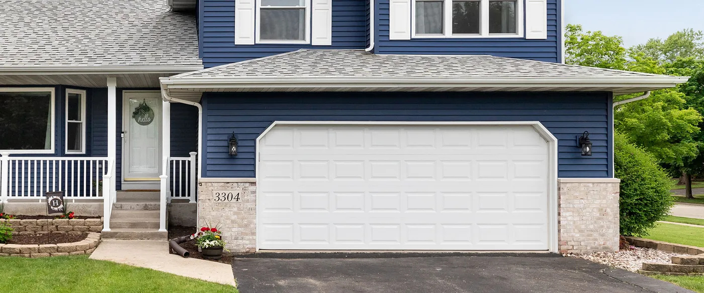 Blue-sided home with a white raised-panel garage door and front porch