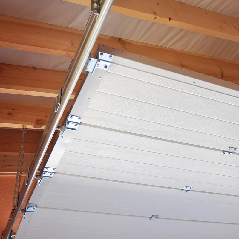 Underside of an open white garage door with its track and hinges below ceiling joists